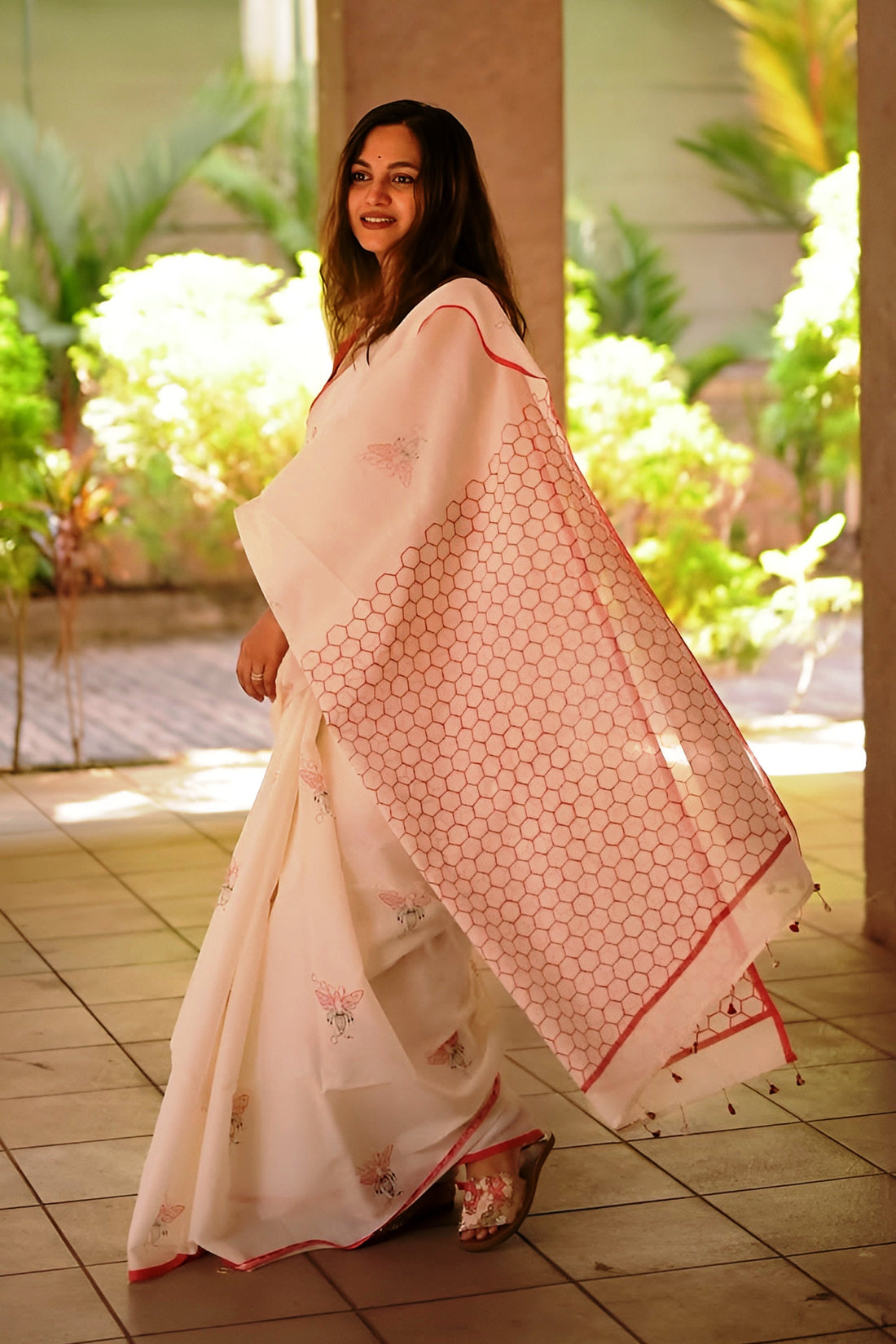 Woman holding a pink saree with a geometric pattern in an outdoor setting
