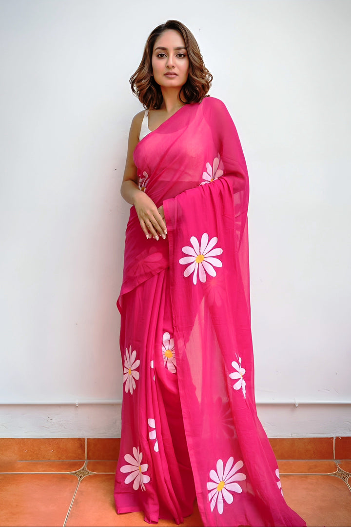 Woman wearing a pink saree with white floral patterns on a white background