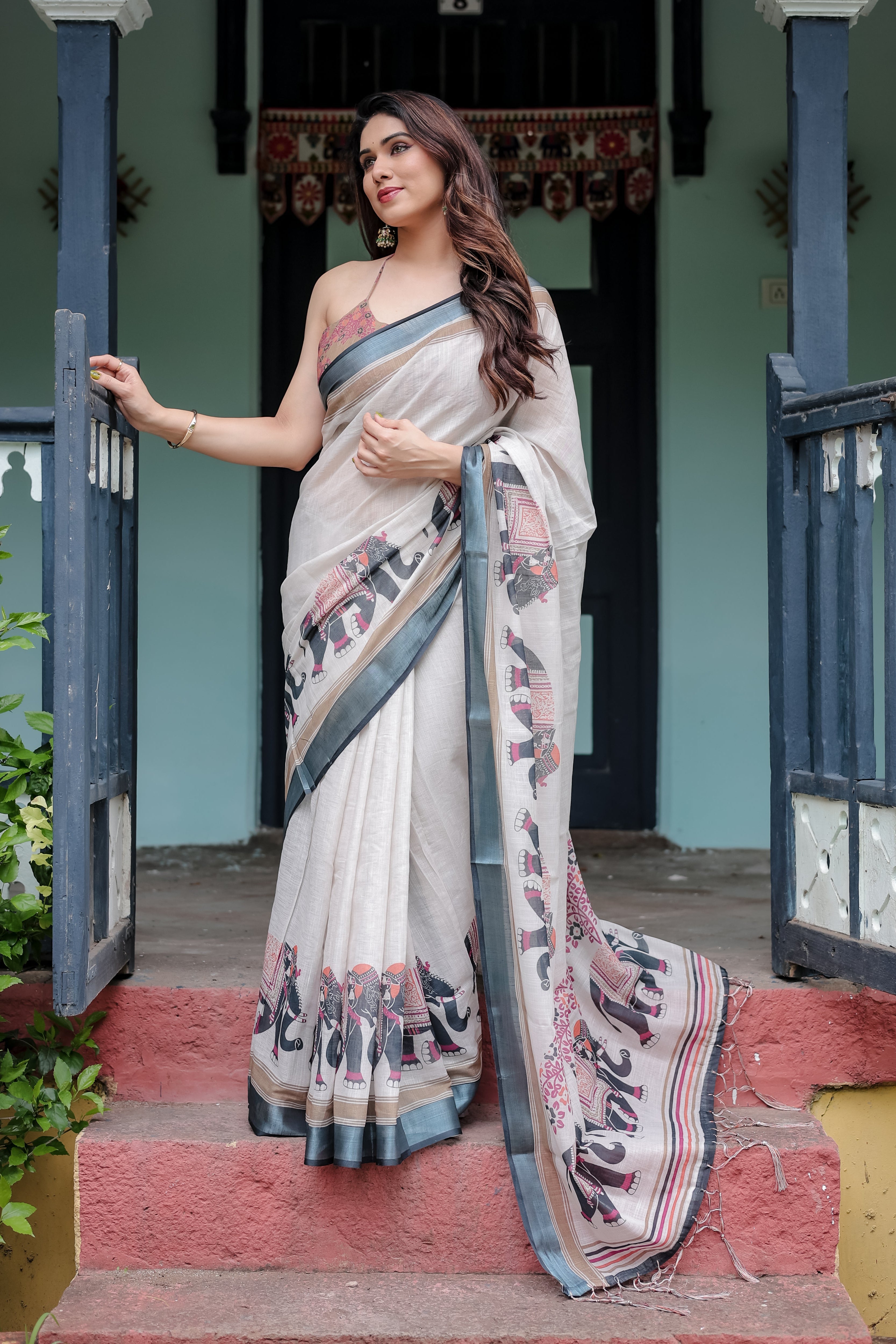 Woman in a saree standing on steps outside a building