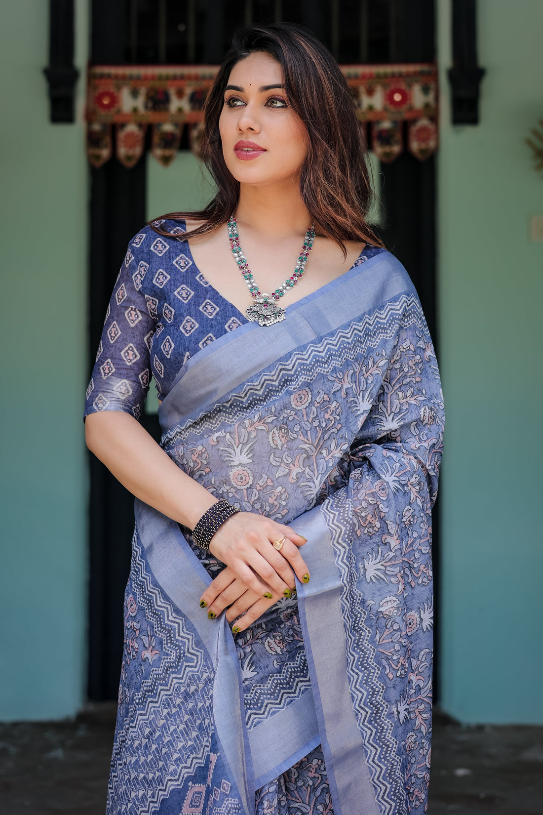 Woman wearing a blue saree with a patterned design indoors.