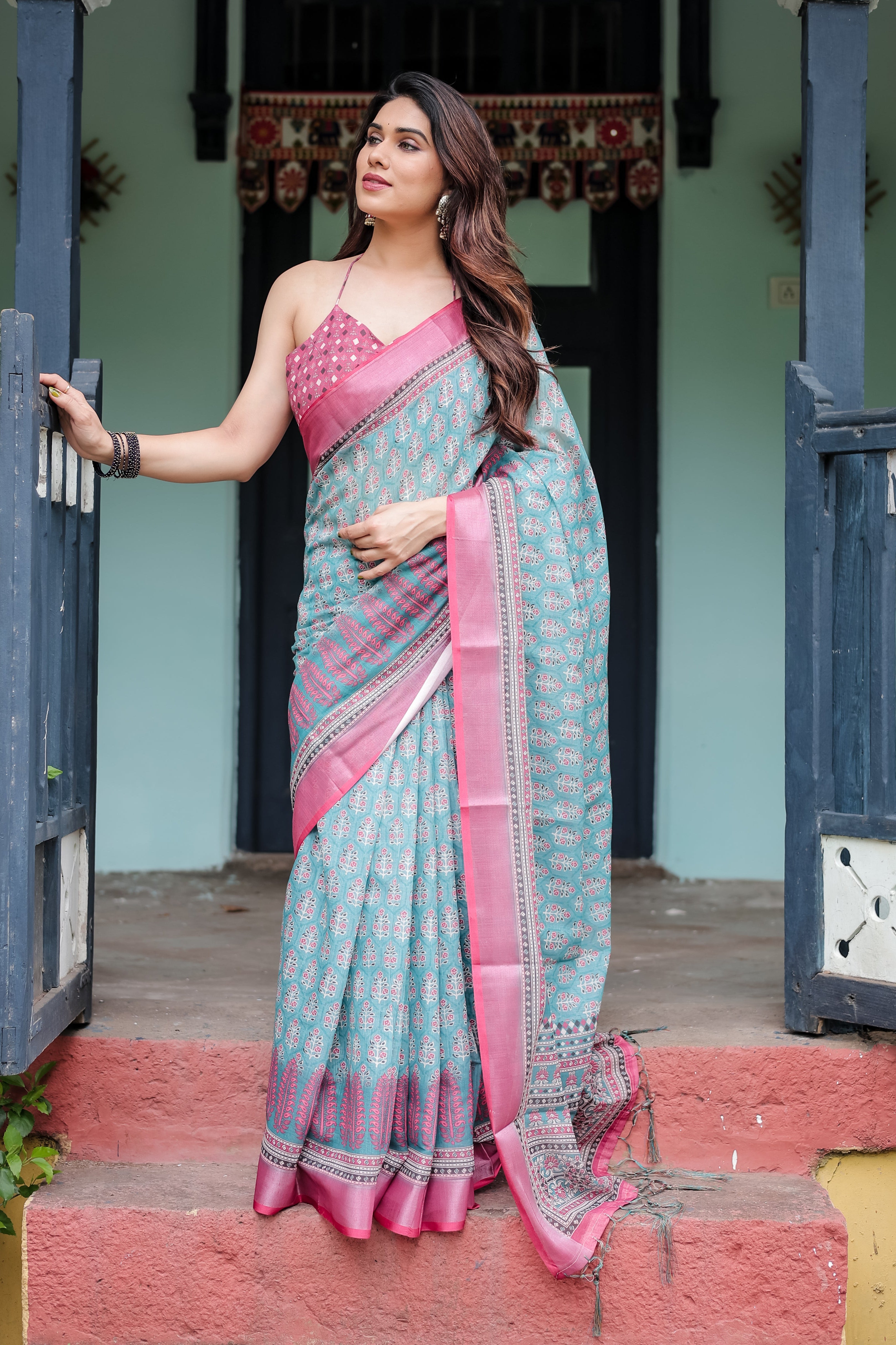 Woman in a pink and blue saree standing outdoors.