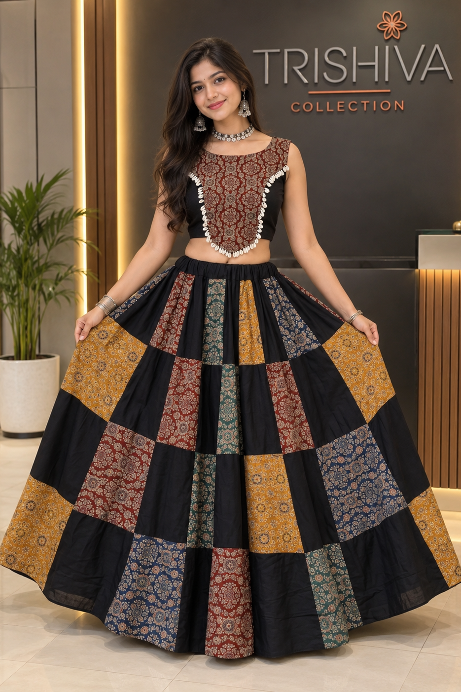 A woman modeling a Trishiva Collection ethnic outfit consisting of a black sleeveless crop top with intricate gold and red embroidery, paired with a matching flared patchwork lehenga skirt featuring multiple patterned panels in gold, red, blue, and black.