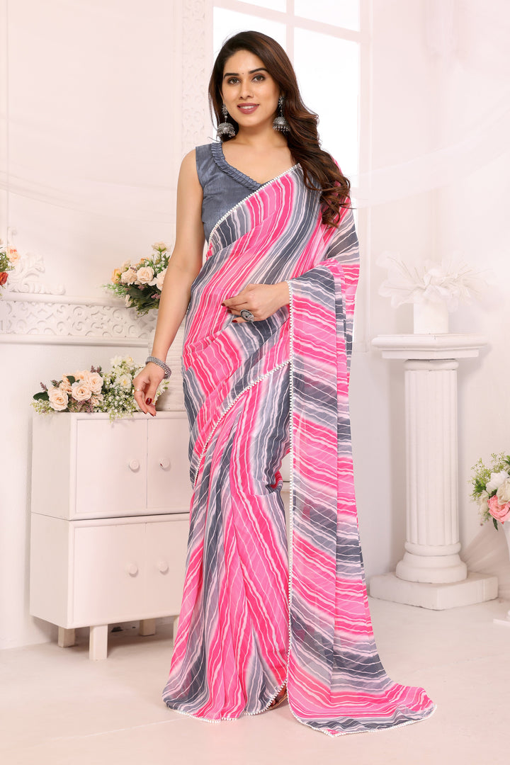 A woman modeling a pink, gray, and white striped saree with a solid gray sleeveless blouse, standing in a bright, white-furnished room.